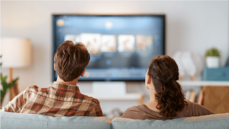 couple on a couch with a tv in the background