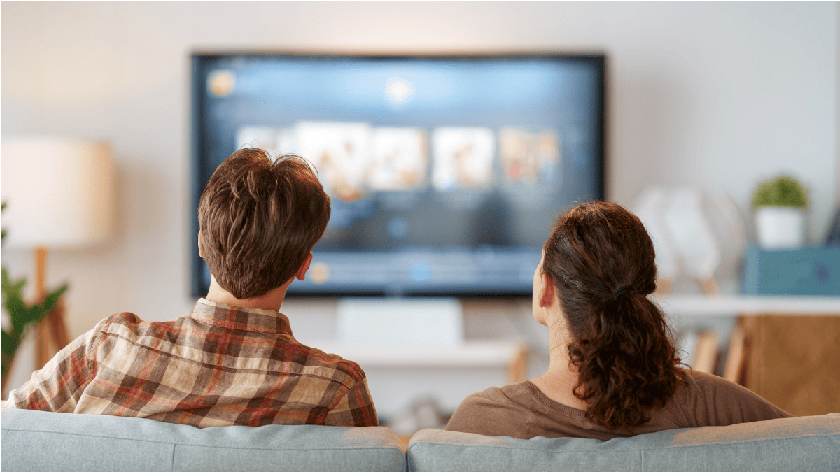 couple on a couch with a tv in the background
